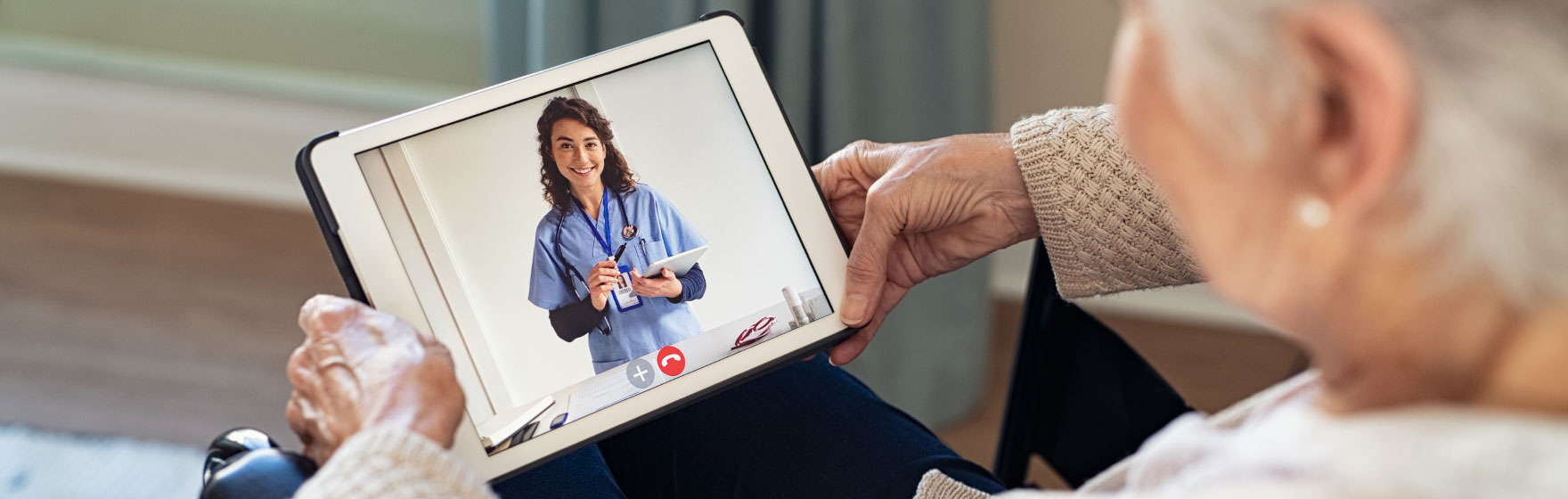 Elderly woman holding a tablet talking to her doctor, telehealth meeting