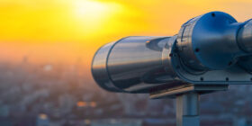 Binoculars or telescope on top of skyscraper at observation deck to admire the city skyline at sunset.