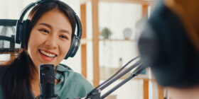 Asia woman records podcast use microphone wear headphones interviewing a guest